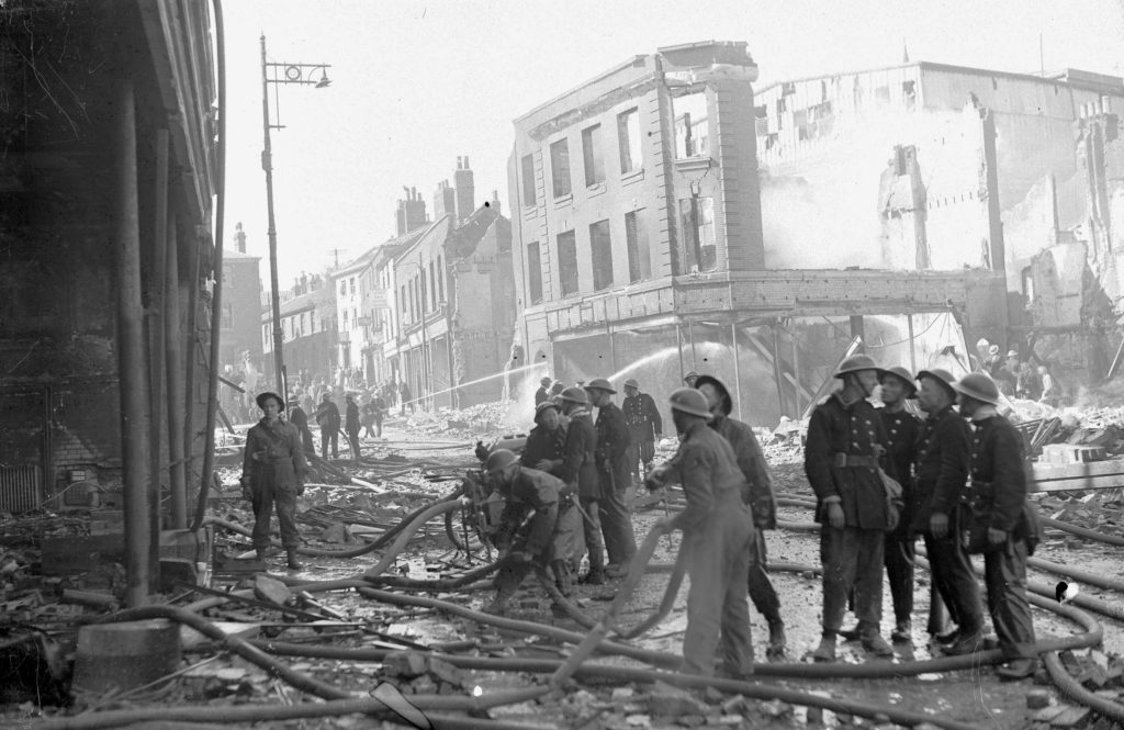 An Air-Raid response team and fire department asses the damage following a raid in Norwich - many buildings are totally destroyed